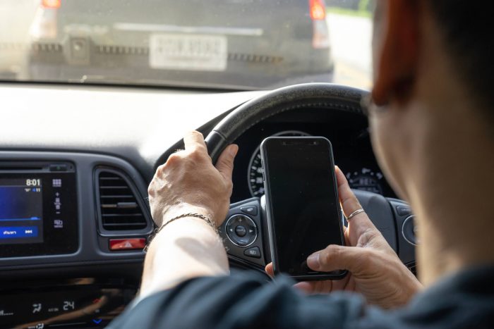 Man texting on mobile phone while driving a car