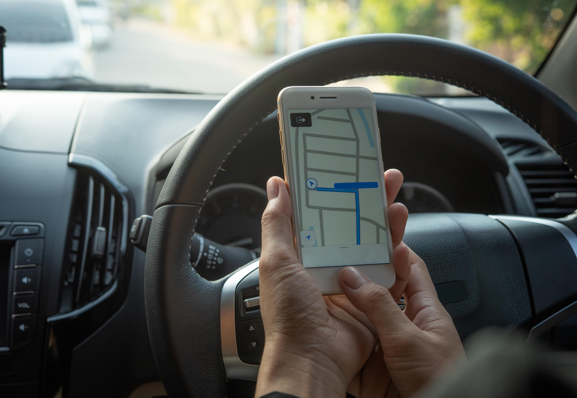 Person holding a mobile phone while driving a car