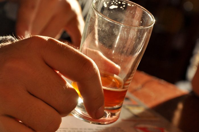 Man’s hand holding middy of beer