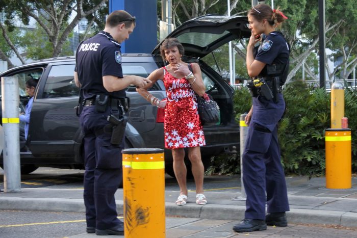 Australia Police officers question a woman wearing a Merry Christmas outfit